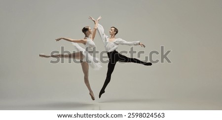 Two ballet dancers leaping in perfect synchronization, arms reaching, bodies forming clear lines against white studio background. Concept of classic dance, freedom, dynamic energy, synergy.