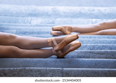 Two ballet dancers wearing stockings and pointe shoes are resting on stone steps. Moment of ballerinas relaxation during practice, with focus on the elegant lines of their legs. - Powered by Shutterstock