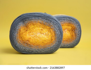 Two balls bright colored cotton yarn and gradient lie yellow background