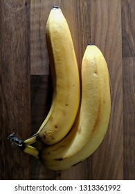 Two Bananas In Stark Lighting On A Wooden Table