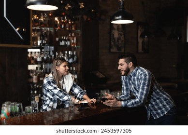 Two barista bartender or waiter workers woman and man working in bar standing and talking, having fun while there is no guests. cafeteria colleagues working and standing at bar counter communicating. - Powered by Shutterstock