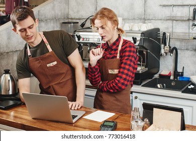 Two Barista Boy And Girl Looking At Laptop In A Coffee Shop. Training Intern