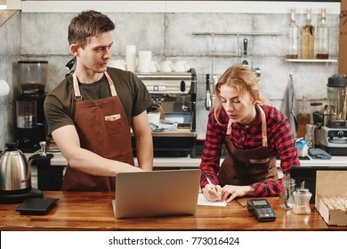 Two Barista Boy And Girl Looking At Laptop In A Coffee Shop. Training Intern