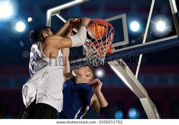 Two basketball\
players in action in gym