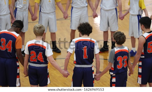 two\
basketball teams hold hands during a pregame\
prayer.