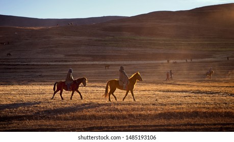 Two Basotho horsemen riding on their horses in the highlands of Lesotho during a sun down in a dried weather in winter - Powered by Shutterstock