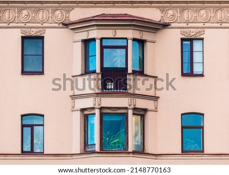 Two bay windows and several windows in a row on the facade of the urban historic apartment building front view, Saint Petersburg, Russia