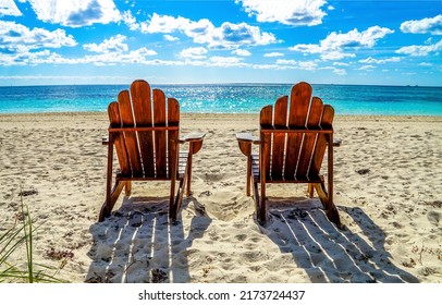 Two beach chairs on a sandy beach. Sandy beach scene. Two chairs on beach resort. Chairs on the beach