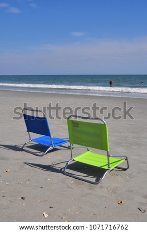 Two beach chairs in the sand.