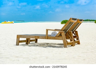 Zwei Liegestühle nebeneinander auf sandigen Ozean mit Blick auf das blaue Meer, flache Felstiefe