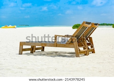 Two beach chairs side by side on sandy ocean front with view over blue sea, shallow depth of field