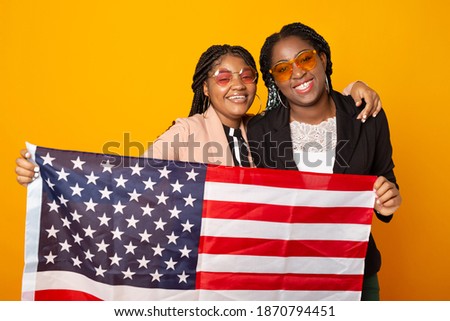 two beautiful african women with american flag on yellow background