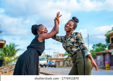 two beautiful African women giving high five,looking cheerful,smiling outdoor-concept on friendship and togetherness
