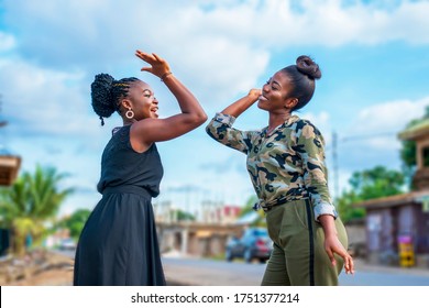Two beautiful African women happily laughing and giving a high five