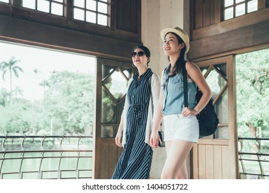 Two Beautiful Asian Girl Friends Travel In Old Japan City Kyoto Sightseeing Visiting Mesuem By Nature Pond. Smiling Young Women Backpacker Walking Looking Around In Wood House By Park Outdoor.