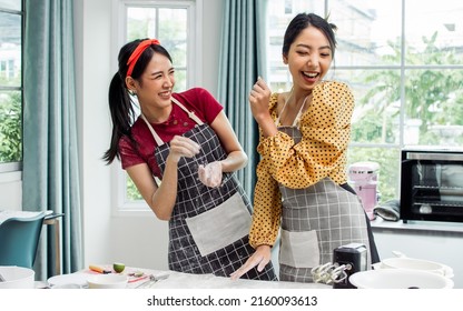 Two Beautiful Asian Women Cooking Food, Making Bread For Breakfast And Bakery, Teasing, Playing Together With Happiness, Fun While Standing In Kitchen At Home On Weekend. Hobby And Lifestyle Concept