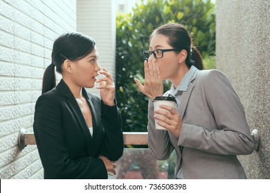 Two Beautiful Asian Women Talking About Office Gossip And Feel Shocked At Rest Time Outdoor Of The Studio.