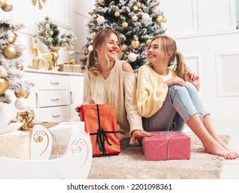 Two Beautiful Blond Women. Models Posing Near Decorated Christmas Tree At New Year Eve. Having Fun, Ready For Celebration. Bright Holiday Of Best Friends Dressed In Warm Winter Sweaters