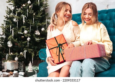 Two Beautiful Blond Women. Models Posing Near Decorated Christmas Tree At New Year Eve. Having Fun, Ready For Celebration. Bright Holiday Of Best Friends Dressed In Warm Winter Sweaters