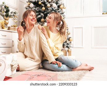 Two Beautiful Blond Women. Models Posing Near Decorated Christmas Tree At New Year Eve. Having Fun, Ready For Celebration. Bright Holiday Of Best Friends Dressed In Warm Winter Sweaters