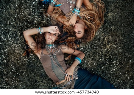Two beautiful boho girls in ethnic jewelry outdoors. Top view
