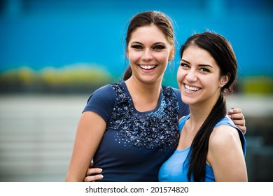 Two Beautiful Brunette Girls Hugging And Smiling At Camera. High School Best Friends. Attractive Woman Having Fun And Laughing On Summer Vacation Outdoors