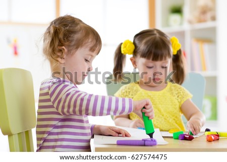 Two beautiful children girls drawing in kindergarten or preschool
