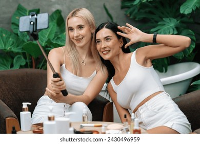 Two beautiful content creator making natural beauty and cosmetic tutorial on green plant garden video. Beauty blogger showing how to beauty care to social medial audience using selfie stick . Blithe