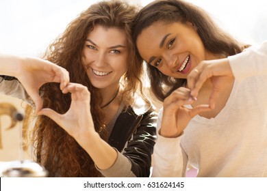 Two Beautiful Ethnic Female Friends Smiling Happily Making Heart Sign With Their Hands African European Diverse Diversity International Unity Friendship Love Happiness Togetherness Cafe Coffee Shop