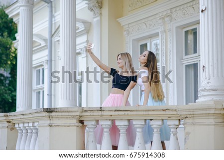 Two beautiful girls in colored skirts near wall