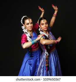 Two beautiful girls are dancing Indian dance. Dancers in Indian costumes in the studio on a black background