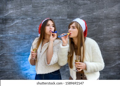 Two beautiful girls in fur jackets and champagne celebrating New Year