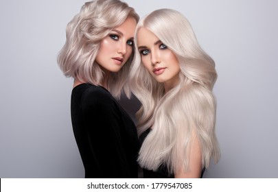 Two beautiful girls with hair coloring in blond. Stylish hairstyle curls done in a beauty salon. Beauty, cosmetics and makeup