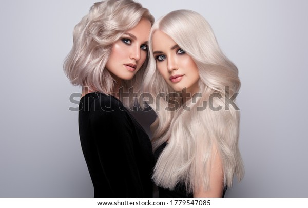 Two beautiful girls with hair coloring in blond.\
Stylish hairstyle curls done in a beauty salon. Beauty, cosmetics\
and makeup