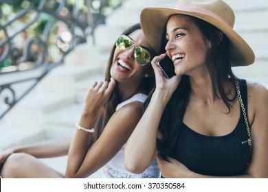 Two Beautiful Girls Laughing While Talking On Phone With A Boy