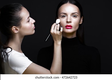 Two Beautiful Girls On A Photo Shoot To Apply Makeup To The Face. Beauty Fashion Model. Photos Shot In Studio