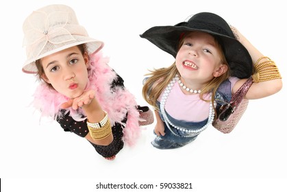 Two Beautiful Girls Playing Dress Up With Hats, Baggy Dresses And Jewelry Over White.