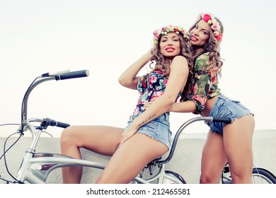 Two Beautiful Girls Twins Ride On A Tandem Bike Outdoors