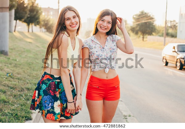 Two chicks in pretty summer outfits walk across the street