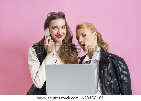 Two beautiful glamor businesswomen with a laptop having a discussion and talking on the phone 