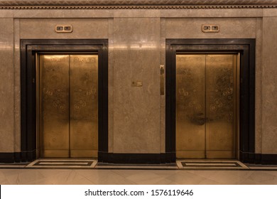 Two beautiful gold door elevators in a marble lobby of a fancy skyscraper building waiting for people in a business environment