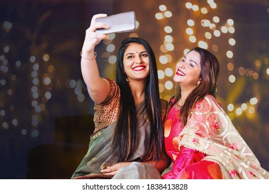 Two beautiful Indian woman taking selfie while wearing ethnic traditional clothes for Diwali or another festival celebration