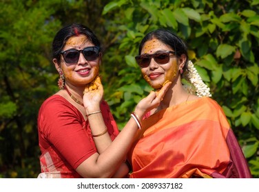 Two beautiful Indian women playing with Turmeric Paste at the time of Haldi Ceremony or Pithi Ceremony. 