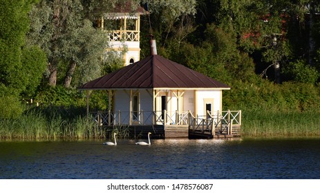 Two beautiful lakeside gazebos and a pair of whooper swans swimming past in soft morning light - Savo region, Finland - Powered by Shutterstock