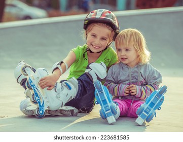 two beautiful little sisters in a roller skates sitting on the street