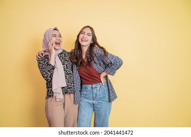 Two Beautiful Muslim Women Laughing And Joking While Embracing With Hands On Shoulders With Copyspace