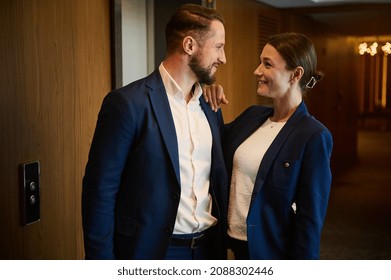 Two Beautiful People, Business Partners, Colleagues Standing Close To Each Other And Flirting Together In The Lobby At The Door Of A Hotel Apartment. Love Affairs At Work, People, Business,intrigues