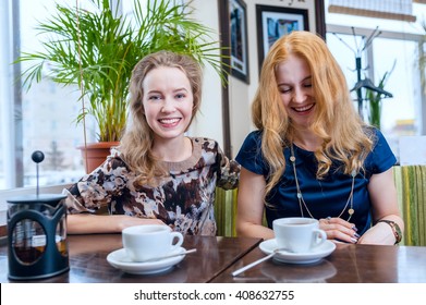 Two Beautiful Smiling Girls Drinking Tea In Cafe Outside