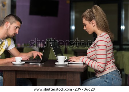 Two Beautiful Students Drinking And Having Fun With Laptop In Cafeteria