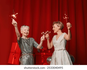 Two beautiful stylish mature senior women in dresses with sparklers and glasses celebrating new year. Happy Ney Year 2025 - Powered by Shutterstock